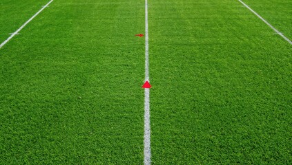 Fototapeta premium American football field featuring vibrant green synthetic turf, ten yard line indicators, and horizontal yard markings in red and white, sports training environment