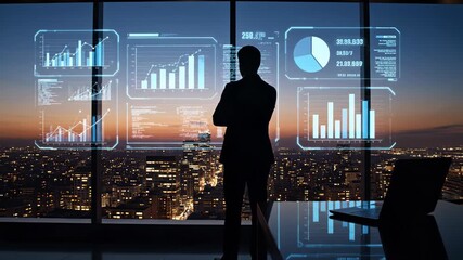 Businessman looking at futuristic holographic financial data charts and graphs overlooking a city at night - Powered by Adobe