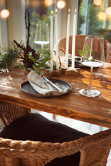 Atmospheric christmas table decoration in a cozy conservatory with festive bokeh lights. Decorations concept for a christmas dinner in restaurant.