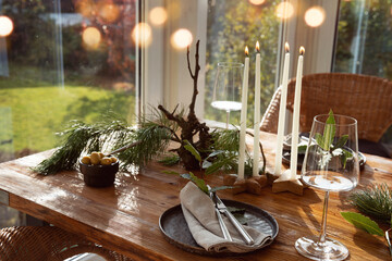 Atmospheric christmas table decoration in a cozy conservatory with festive bokeh lights. Decorations concept for a christmas dinner in restaurant.