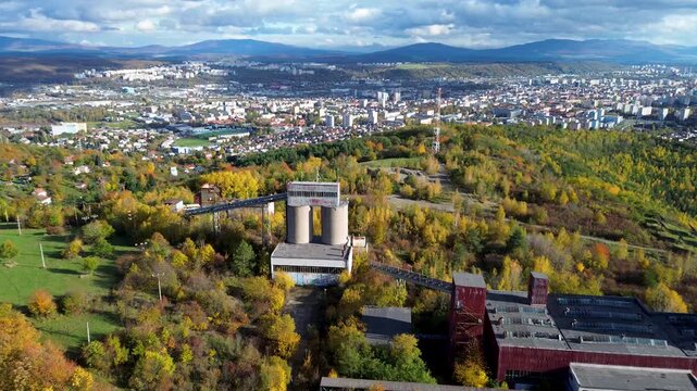 Aerial view of a solar power plant and old magnesite mine buildings near Ko&scaron;ice, Slovakia. Renewable energy panels amidst autumn forest and city skyline