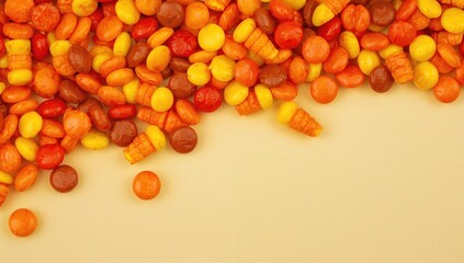 Fototapeta premium A collection of round autumn-hued candies and corn-shaped sweets, seasonal treat for Halloween
