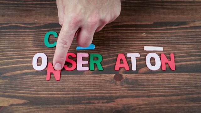 Conservation Concept with Colorful Wooden Letters and Hand on Brown Table - Powered by Adobe