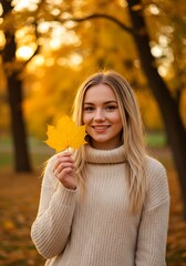 Smiling woman holding a yellow leaf in an autumn park.