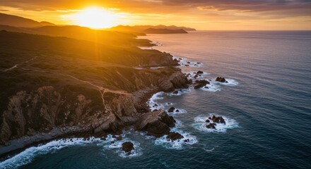 Naklejka premium Brilliant sunlight illuminates rugged coastline meeting the deep blue ocean water at dusk