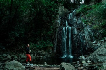 Traveler admiring a waterfall in the heart of the forest