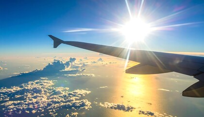 Aerial shot of airplane wing soaring through a bright sunny sky, overlooking a sea of clouds and shimmering ocean