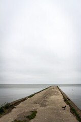 Fototapeta premium Old concrete pier under a cloudy sky in Nida, Curonian Spit and Curonian Lagoon, Lithuania
