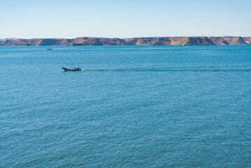 Motorboats sailing the calm blue waters of Nasser lake, Egypt, close to the archeological site of Abu Simbel. Blue water in the foreground. With copy-space.