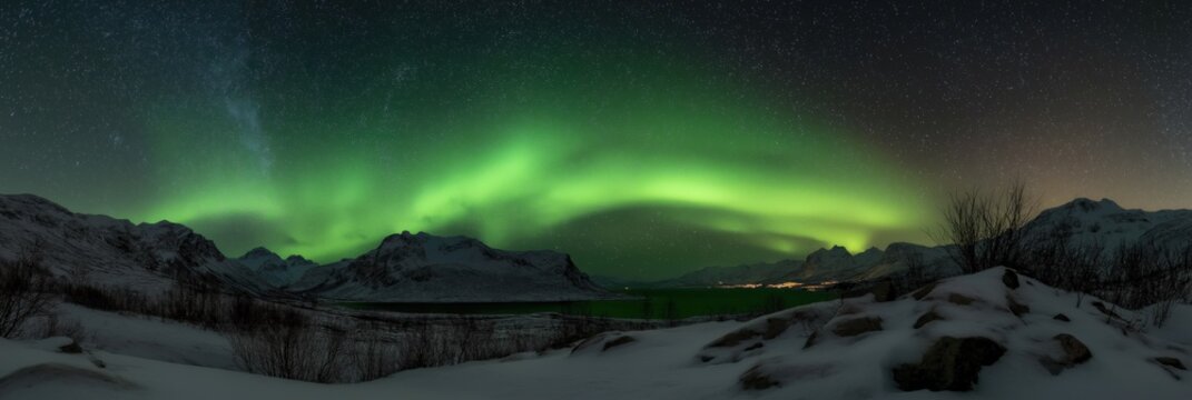 Stunning northern lights dancing over snowy mountains and starry night sky
