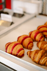 Appetizing freshly baked berry raspberry croissants in the bakery window.