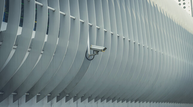 A modern white CCTV security camera mounted outdoors on a building, representing surveillance, protection, and modern technology.