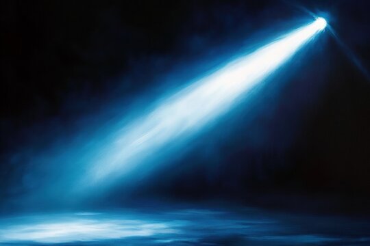 Bright blue spotlight beam piercing through dark space with illuminated floor area and smoky atmospheric effect