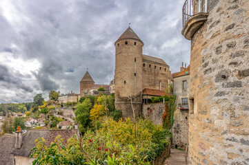 Obraz premium Semur-En-Auxois, France - 11 30 2024: View the landscape, Armancon river with autumn colors, Margot Tower and Prison Tower of the Medieval City from Fourneau staircase