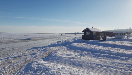 Winter river under a bright spring sky with a birdwatching hut