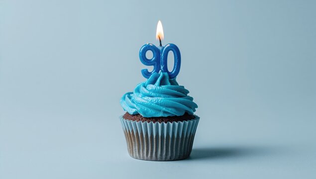 Blue cupcake topped with a candle in the shape of the number 90, celebration theme