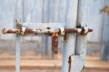 Rusty gate latch, Old weathered latch and corroded gate locking mechanism, Abandoned gate featuring rusted latch and deteriorated locking hardware consistent with neglect