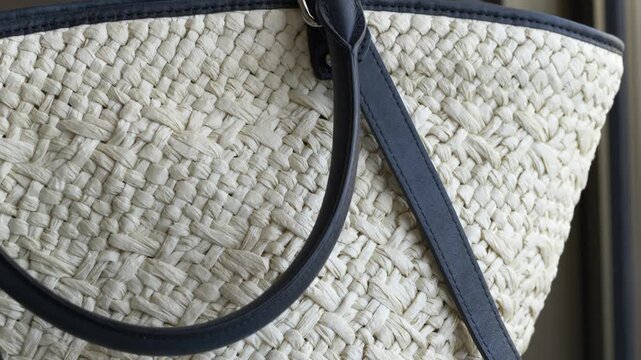 Ivory raffia tote with leather strap, closeup revealing woven pattern and black handle, sunlight through window, polished buckle detail, summer resort vibe for fashion and retail styling