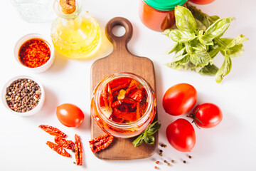 Dried organic tomatoes preservation with herbs and olive oil in jar.	