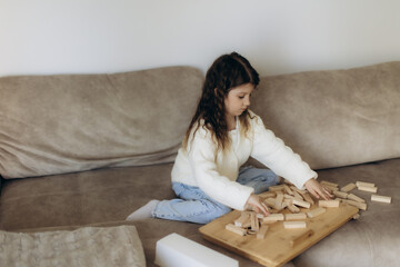Young Girl Playing With Wooden Blocks on a Couch