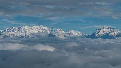 Obraz premium Aerial view of snow-covered peaks enveloped in clouds, showcasing the tranquil allure of mountainous terrain