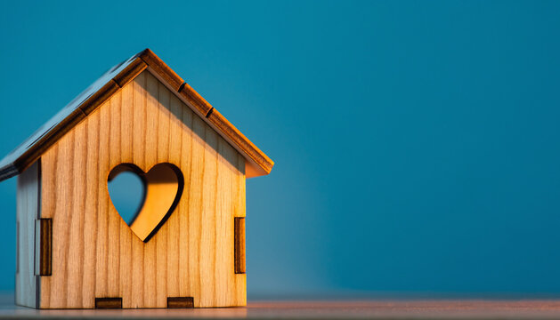 Home sweet home, house wood with heart shape on wooden and blue background, copy space.
