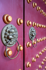 Intricate brass knockers adorn a vibrant purple door