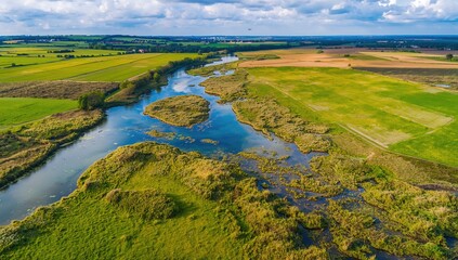 Obraz premium Aerial view of Alkborough Flats showcasing wetlands and open fields along a river, highlighting preservation efforts