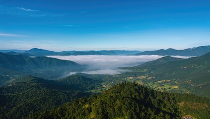 Naklejka premium Aerial view of a misty valley landscape, showcasing natural fog cover, seasonal change