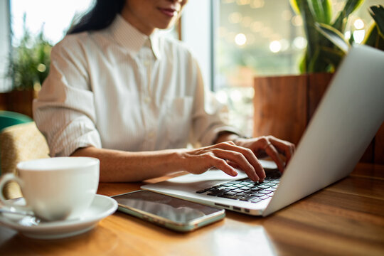 Adult woman focused typing on laptop at cafe