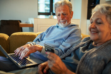 Senior couple shopping online at home, focused and content