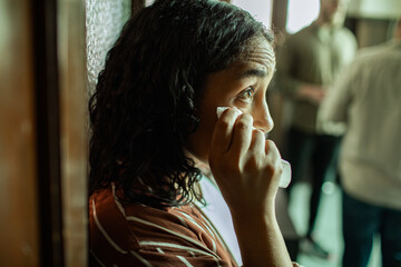 Adult woman wiping tears with tissue indoors, feeling sad