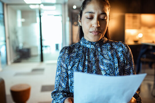Adult woman reviewing paperwork with concerned expression in office