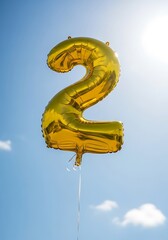 Golden Number Two Balloon Floating in a Bright Blue Sky.
