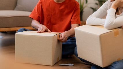 Asian adult couple packing moving boxes new home apartment living room floor preparing relocation domestic space collaboration teamwork