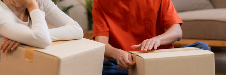 Asian adult couple diligently packing moving boxes at home preparing for smooth house relocation...