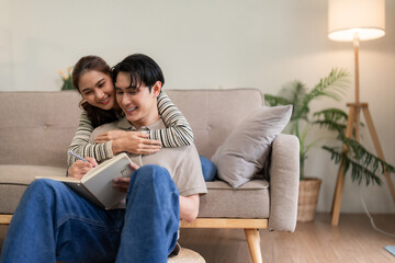 Young Asian Couple Enjoys Cozy Home Life Bonding Over Shared Activities Writing Notes Together Modern Living Space