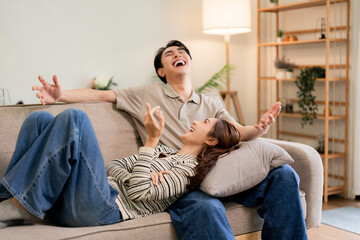 Asian young adult couple deep laughter home living room joy relaxation happy moments bonding cheerful adults cozy modern interior