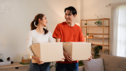 Asian adult couple move home carrying boxes new apartment happy relocation partnership young adults homeowner journey
