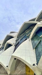 Contemporary mosque facade with geometric marble panels and reflective glass design. A stunning example of modern Islamic architecture and cultural artistry.