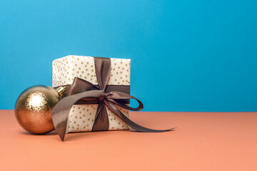 Christmas gift box and brown ornament on blue and orange background. Christmas greeting card....