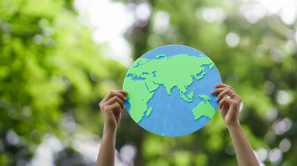 Hands holding earth globe paper cutout for Sustainable environment Development. Eco-friendly Green business, carbon reduce emission to Net zero. Circular economy, Earth Day, and ESG concept.