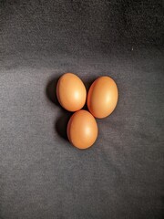 Top View of Three Organic Brown Eggs on a Dark Fabric