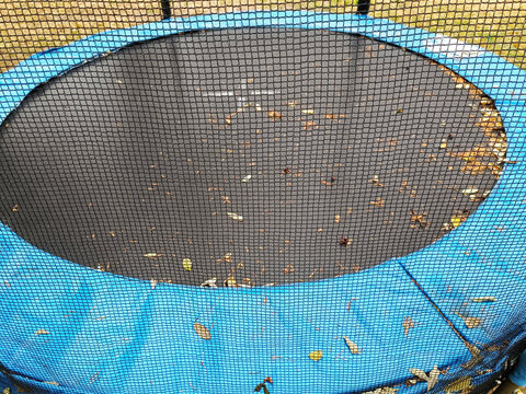 Dirty Trampoline with Autumn Leaves &ndash; Seasonal Garden Scene with Fallen Foliage
