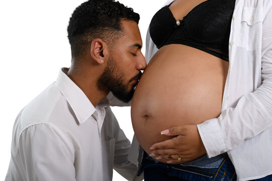 Expectant father lovingly kisses his pregnant partner's baby bump