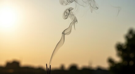 Delicate tendrils of fragrant smoke ascend against a warm, diffused twilight sky
