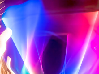 Colorful, fluorescent swirls of light create a dynamic and energetic abstract composition. Blurred streaks of purple, blue, and gold give the impression of rapid, surreal movement.