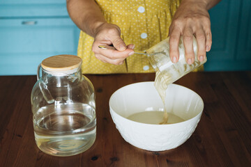 Woman pouring sourdough starter into bowl while preparing dough  