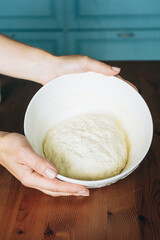 Hands holding a bowl of elastic dough for making sourdough bread  