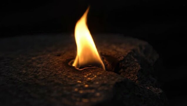 Close up of a single flame burning in darkness.